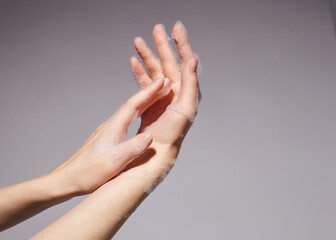 womens hands in thick soap suds on a gray background 
