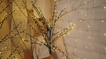 Branch lights with handwritten notes on a rustic wall, creating a festive mood