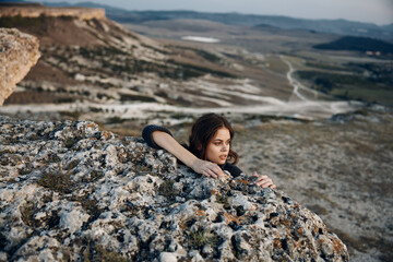 Serene young woman sitting on rock in mountain valley with breathtaking view