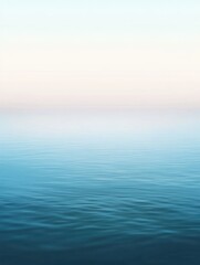 Obraz premium A serene view of calm ocean waters blending with a pastel sky.