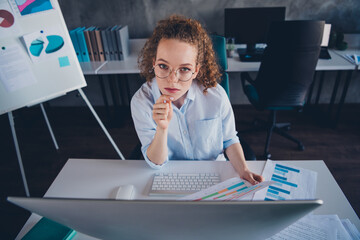 Focused businesswoman analyzing data charts at her workstation in modern office setting
