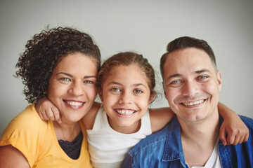 Portrait, parents and child with hug for love, security and bonding together of relationship. Girl, mom and dad with embrace for care, support and family connection for childhood in studio background