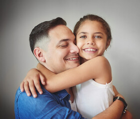 Fototapeta premium Happy, father and daughter hug with love for affection, security and bonding together of relationship. Smile, girl and man with embracing for care, comfort and family connection on studio background
