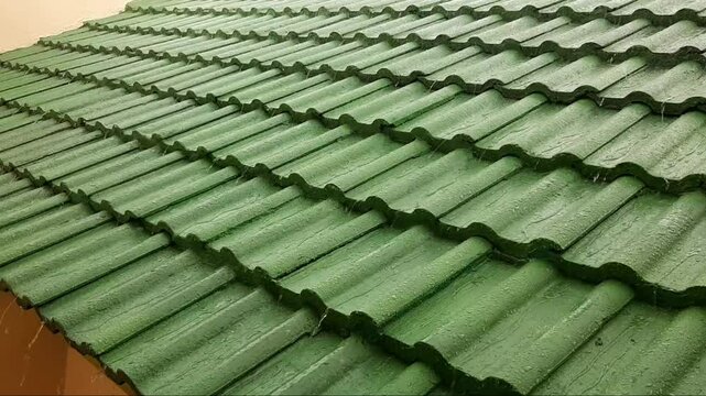 Detailed Video of Drizzling Rainwater Falling, Hitting The Green Concrete Tile Roof and Flowing Smoothly Into The Gutter Pipe Drain. Protective Building Materials From Leaks. Cool Afternoon Atmosphere