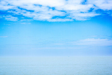 Fototapeta premium a beach with a few people on it and a sailboat in the distance.