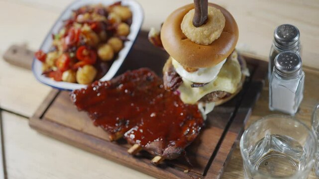Top view of a combo dish including burger bacons with sauce and a salad of potato