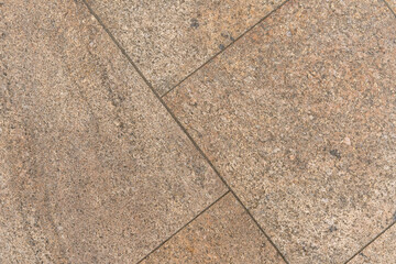 Closeup of walkway with marble design tiles walkway. Gaps between tiles arranged diagonally. Creamy beige to brown color.