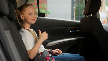 Caring Caucasian mother female woman auto driver fastening seat belt little girl child kid happy...