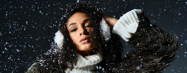 A stunning brunette woman showcases stylish winter wear, featuring earmuffs and a cozy faux fur...