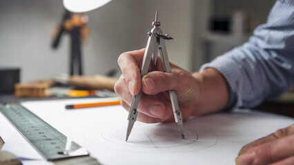 Architect or Engineer Using Compass for Precise Technical Drawing on Paper
