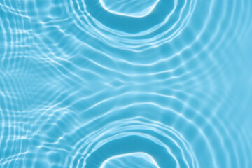Blue water with ripples on the surface. Defocus blurred transparent blue colored clear calm water surface texture with splashes and bubbles. Water waves with shining pattern texture background.