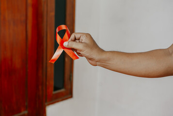 Hand holding Red Ribbon for December World Aids Day (acquired immune deficiency syndrome), multiple myeloma Cancer Awareness month and National Red ribbon week. Healthcare and world cancer day concept