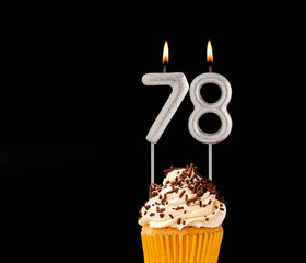 Birthday cupcake on black background - Number 78 shaped candles.