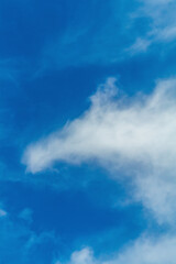 A vertical shot of the sky, the blue of which is partially obscured by a smoke-like cloud, scattering in the wind into small pieces. Environment, protection of nature, atmosphere, air