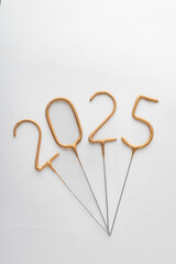 Numbers 2025 made from golden sparklers on white background. Celebrating New Year, close-up....