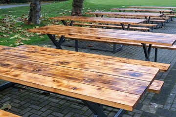 Fototapeta premium Empty picnic tables standing on a brick patio in a park