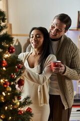 A couple joyfully decorates their Christmas tree together, embracing the spirit of the holiday.