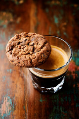 Chocolate cookie and Coffee in glass cup on rustic wooden background. Close up.