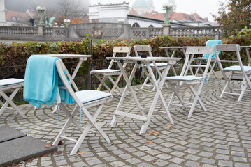 Empty tables and chairs with towel overlooking ljubljanica river in ljubljana, slovenia
