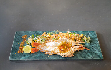 Lobster Pad Thai is served with yellow noodle, fried tofu, cress, bean sprouts, chilli power, garlic chives, and lime put on a rectangular plate.