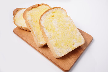 Buttered bread cut into slices on a wooden tray white background
