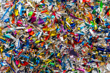 Vibrant and colorful metallic confetti background with various shapes and shiny textures.