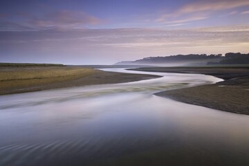 Fototapeta premium Serene coastal landscape with a meandering river under a peaceful sky.