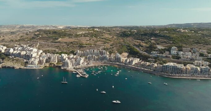 Panoramic Aerial Footage of Bugibba Marina in Malta Showcasing Tourist Friendly Mediterranean Cityscape with Yachts and Boats Along the Coastline. High quality 4k footage