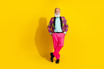 Full size photo of positive old man boyfriend wearing glamour outfit standing with hands pockets isolated yellow color background