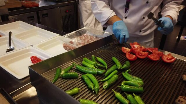 Chef prepares grilled tomatoes and green peppers as a flavorful side dish to complement a main course