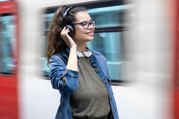 Pretty young girl listening to music with headphones at the train station
