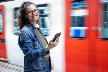 Pretty young girl holds her phone at the train station