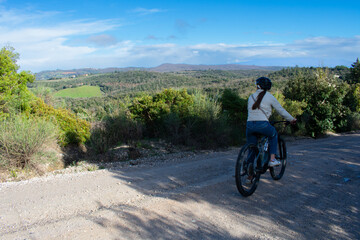 Fototapeta premium Female on Electric Bike taking a trail ride through Tuscany Italy