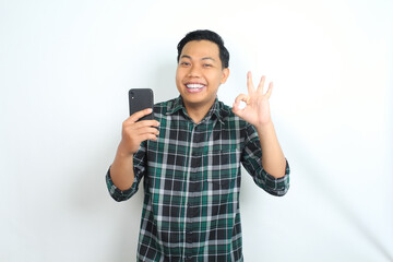 happy asian man holding smartphone wear casual shirt show ok sign, approved, yes gesture, with smiling face isolated on white background