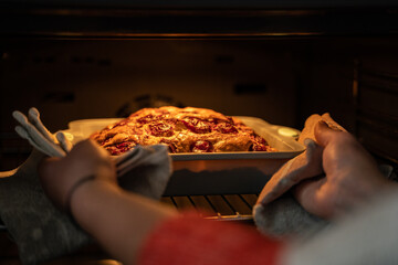 Closeup of warm light homemade cake in the domestic oven, process of making and baking pie in oven at the modern kitchen, food cooking, culinary and people 