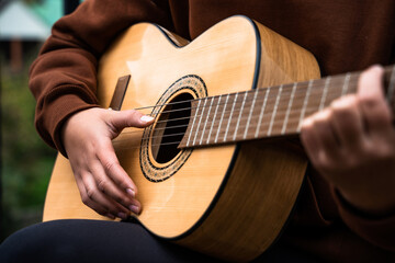 Fototapeta premium Young woman playing acoustic guitar outdoor, close up of teenage girl plays guitar, sitting relaxing and unwinding on weekend, leisure, music, hobby, lifestyle concept, happy guitarist