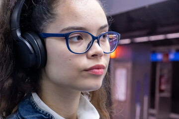 Pretty young girl listening to music with headphones inside the train