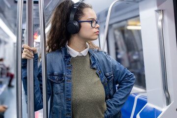 Pretty young girl listening to music with headphones inside the train