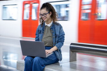 Girl waiting for the train and using her laptop