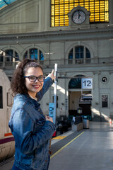 Girl at train station points to clock