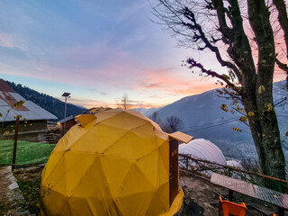 geodesic and swiss tents overlooking manali valley at sunset at a popular glamping spot near hampta village for eco freindly and comfortable adventure stays