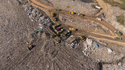 The truck is collecting garbage in a large garbage pile.
