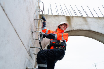 A female engineer inspects the inside of a large concrete pipe. Workers build a pipeline to...