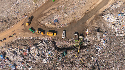 The truck is collecting garbage in a large garbage pile.