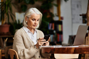 A stylish mature woman checks her smartphone while seated at a charming cafe, immersed in thought.