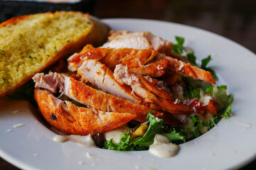 Caesar salad with juicy grilled chicken breast, savory croutons of fresh whole wheat bread toasted with chasnok and a whole array of organic healthy vegetables, dressed with a sauce.