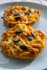 Pumpkin grated roasted patties, rosti or latkes, made fron squash and potato decorated with pumpkin seeds