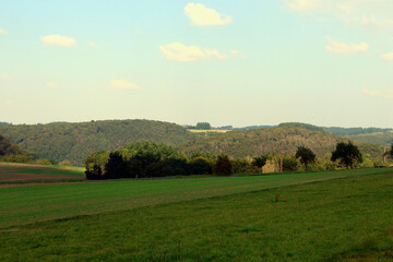 Fototapeta premium Hügelige Landschaft bei Kennfuss, nahe Bad Bertrich, in der Eifel im Landkreis Cochem-Zell. Aussicht vom Wanderweg Wasserfall-Erlebnisroute, der 2023 zu Deutschlands schönstem Wanderweg gewählt wurde.