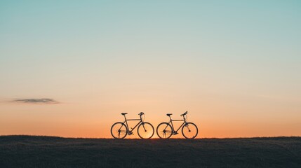Fototapeta premium Two bicycles stand silhouetted against a colorful sunset horizon, evoking a sense of adventure and tranquility.