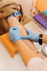 Healthcare professional applying cotton on patient's arm after blood collection in a medical clinic